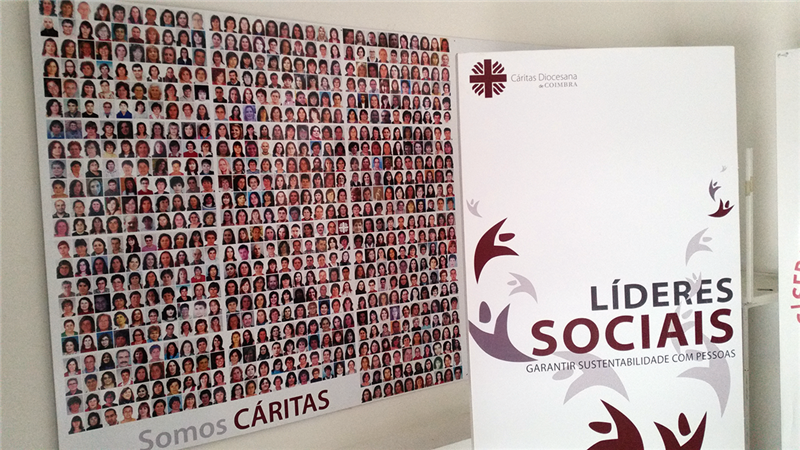 Ein Plakat mit Porträtfotos und dem Slogan 'Somos Caritas' und einem Roll-up der diözesanen Caritas Coimbra in Portugal (Markus Lahrmann)