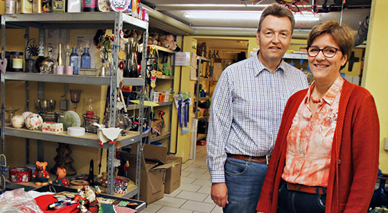 Porträt: Renate und Peter Jendreiko in einem einfach gehaltenen Ladenlokal mit Stahlregale, in dem Waren ausgegelegt sindn