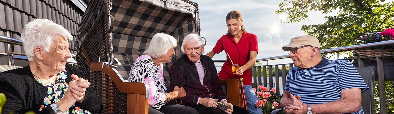 Senior:innen sitzen in und vor einem Strandkorb.