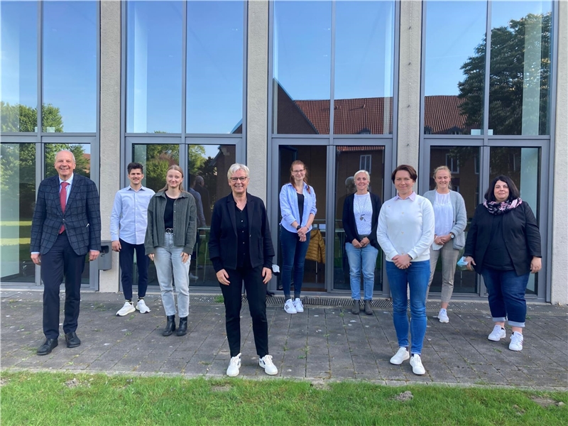 Auf dem Bild sehen Sie neun Personen, die im Innenhof des Caritasverbandes der Diözese Münster sehen.