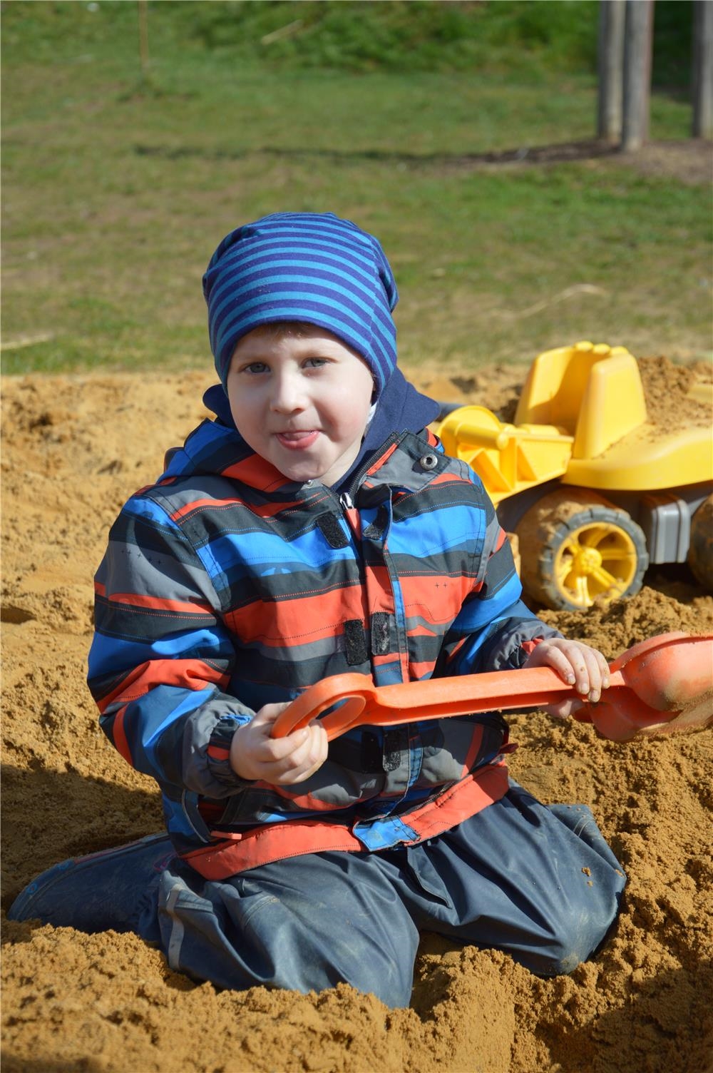 Ein Junge kniet im Sandkasten und hält eine Schaufel in den Händen. (Caritasverband Trier e. V.)