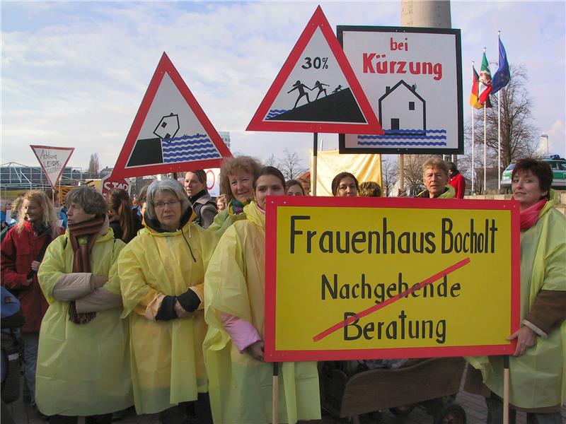 Das Foto zeigt eine Gruppe von Frauen in gelben Regenmäntel, die Schilder in die Höhe halten.