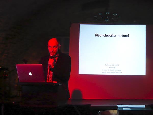 Mann am Rednerpult, im Hintergrund Projektion einer Grafik mit der Beschriftung „Neuroleptika minimal“ (Caritasverband Darmstadt e. V.)