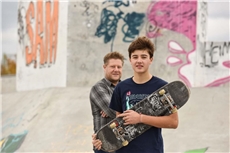 Ein Quartiersarbeiter und ein Junge mit einem Skateboard stehen in einem Skatepark / Deutscher Caritasverband/Harald Oppitz, KNA
