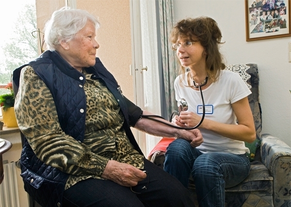Eine Pflegekraft misst bei einer Bewohnerin eines Altenheims den Blutdruck