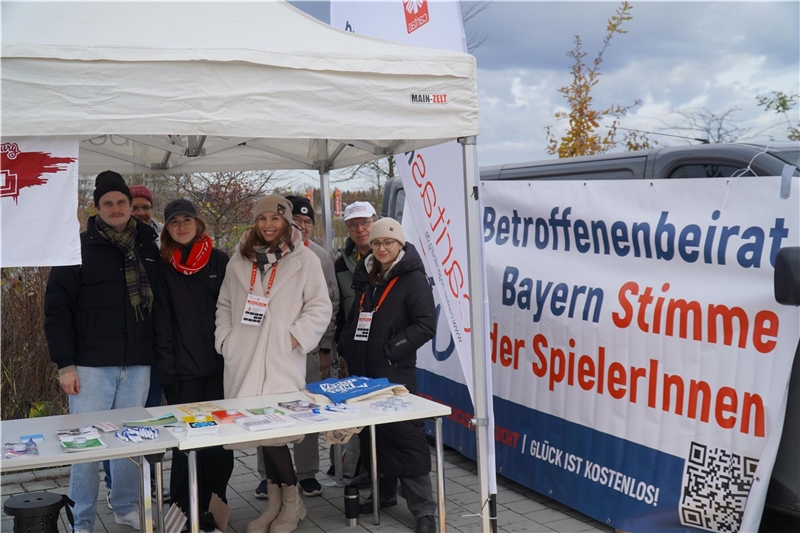 Berater stehen am Caritasstand am Stadion