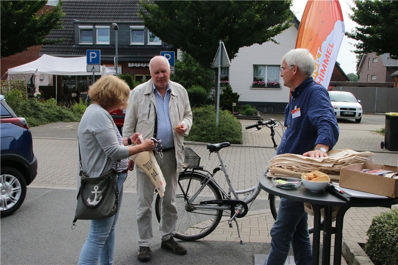 Das Foto zeigt drei Menschen, die sich an einem Stehtisch unterhalten.