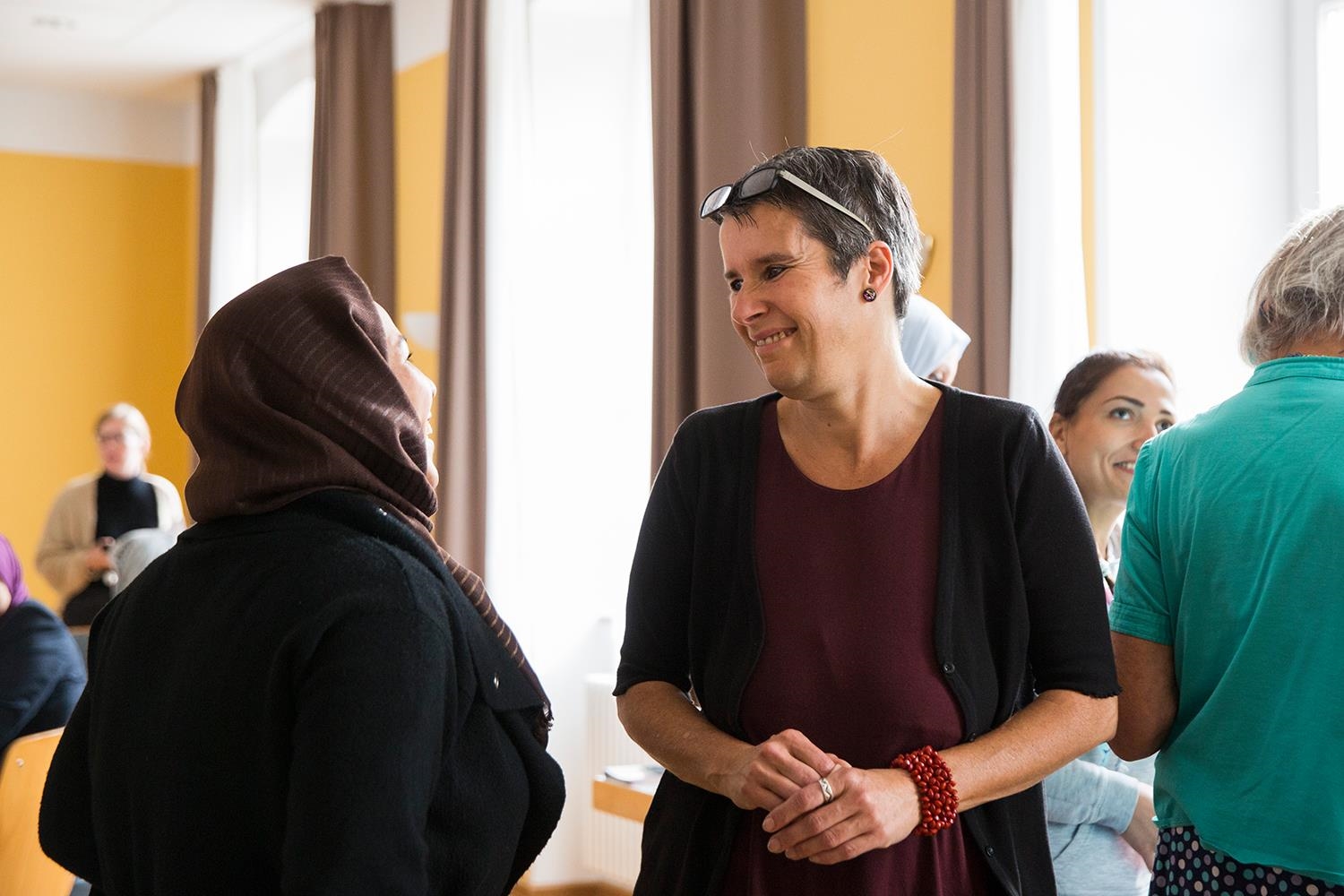 Eine Frau mit kurzen Haaren spricht mit einer Frau mit Kopftuch (Deutscher Caritasverband e. V. / Sebastian Pfütze)