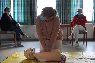 Eine Pflegerin übt an der Puppe die Herzdruckmassage
