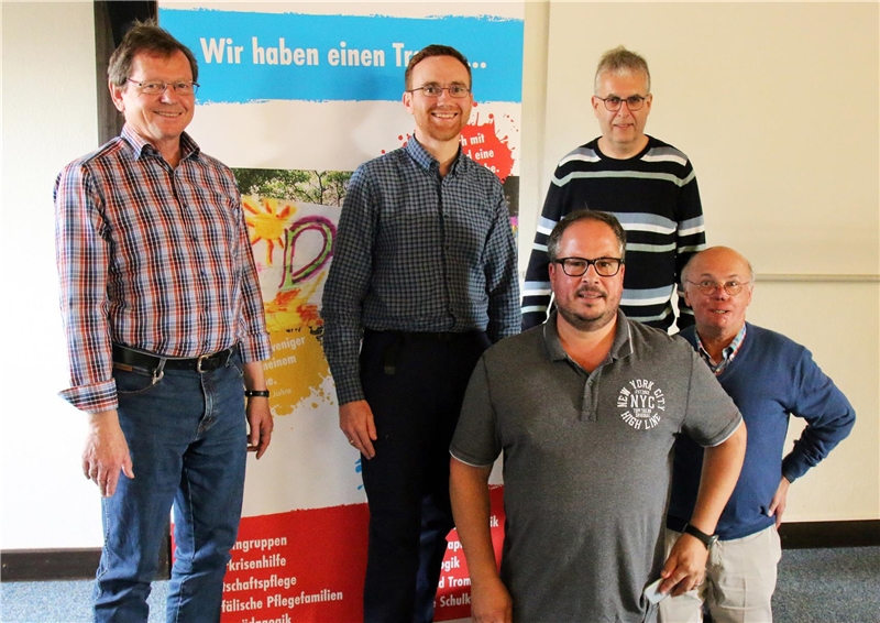 Das Foto zeigt eine Gruppe von fünf Männern vor einem bunten Rollup.