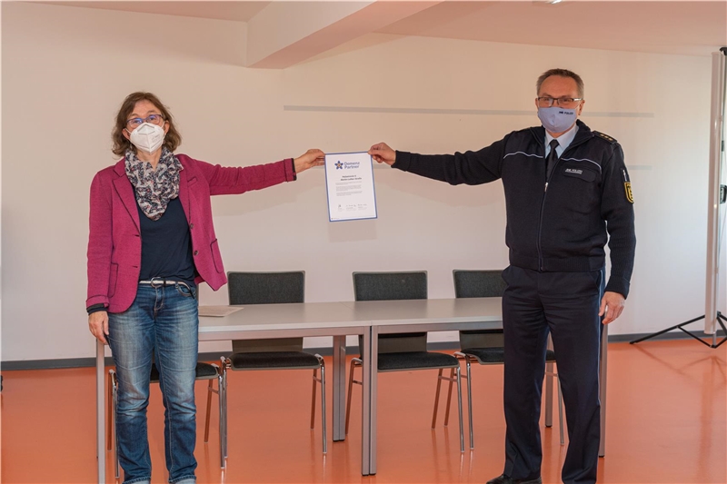 Frau Oehl vom Netzwerk Demenzfreundliches Bad Cannstatt und Polizeirevierleiter halten die Urkunde in die Höhe. 