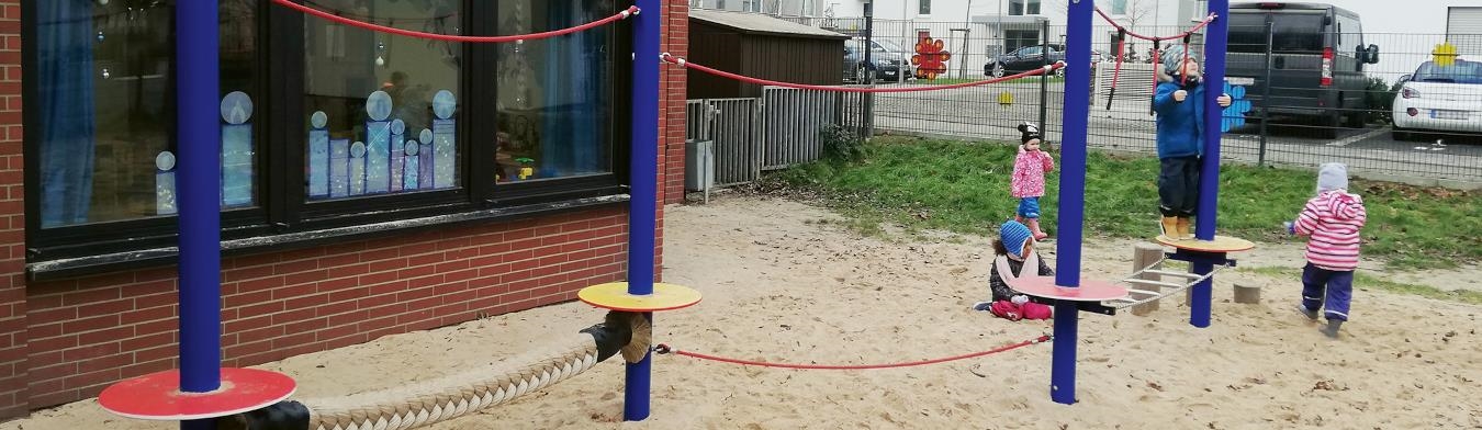 Drei Kinder spielen im Sand im Außengelände der KiTa