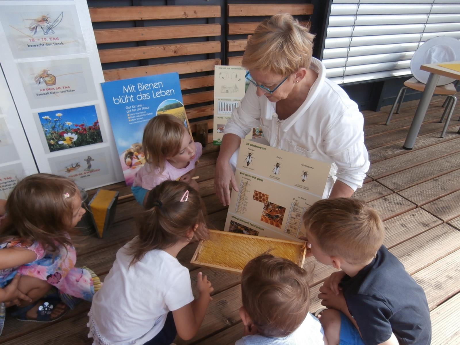 Eine Imkerin ist von fünf Kindern umgeben und erklärt etwas anhand einer Schautafel (© Caritasverband Worms e.V.)