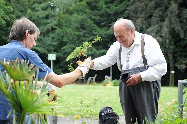 Ein junger Mann reicht einem älteren Mann einen Blumentopf