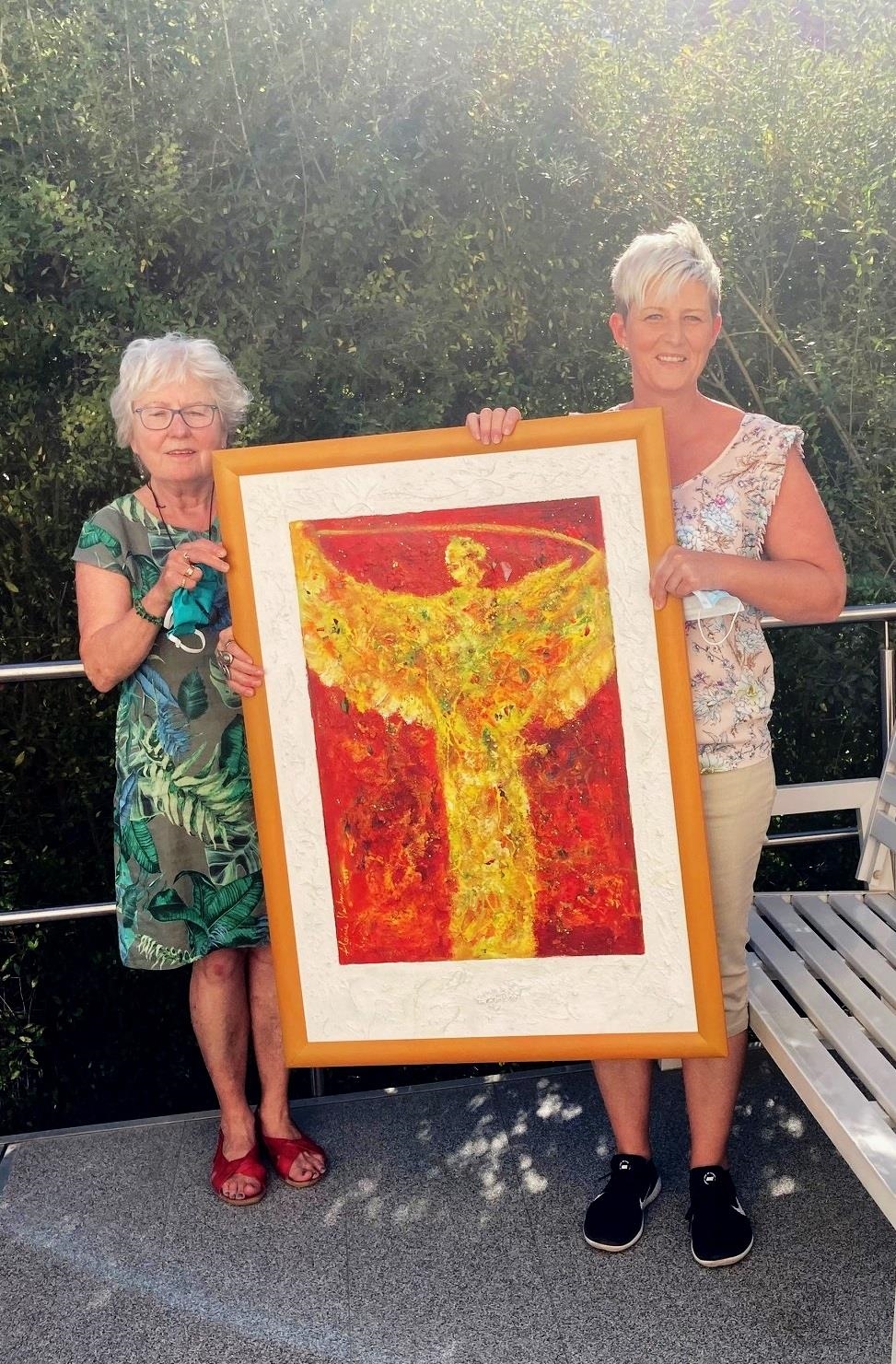Von links nach rechts: Aloisia Hartmeier und Tanja Zahn mit dem Bild: Engel der Sonne oder Engel des Lichts: Der Engel ist gemalt in Collage Acryl auf geschöpftem Papier. (© Caritasverband Worms e. V.)