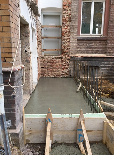 Außenaufnahme, Detail der Baustelle des neuen Treppenhauses. Unterhalb einer brettergesicherten Tür ist in einer Verschalung ein neuer Boden gegossen worden. (Caritasverband Darmstadt e. V. / M. K. Triebel)