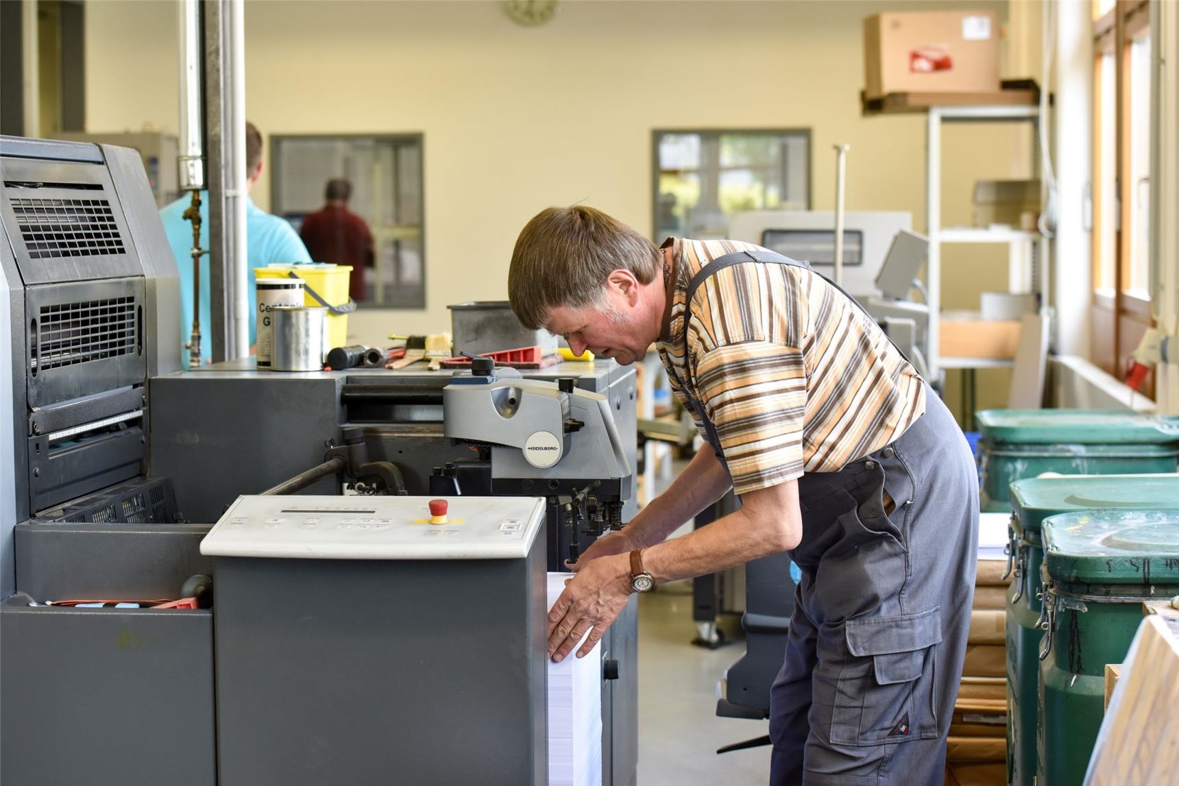 Mann mit Behinderung in Arbeitskleidung bedient eine Maschine (Deutscher Caritasverband / Harald Oppitz, KNA)