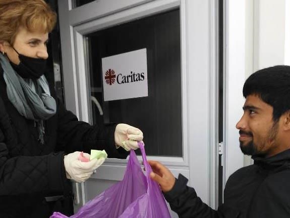 Frau übergibt Tüte an Flüchtling (Foto: Caritas Bosnien Herzegowina)