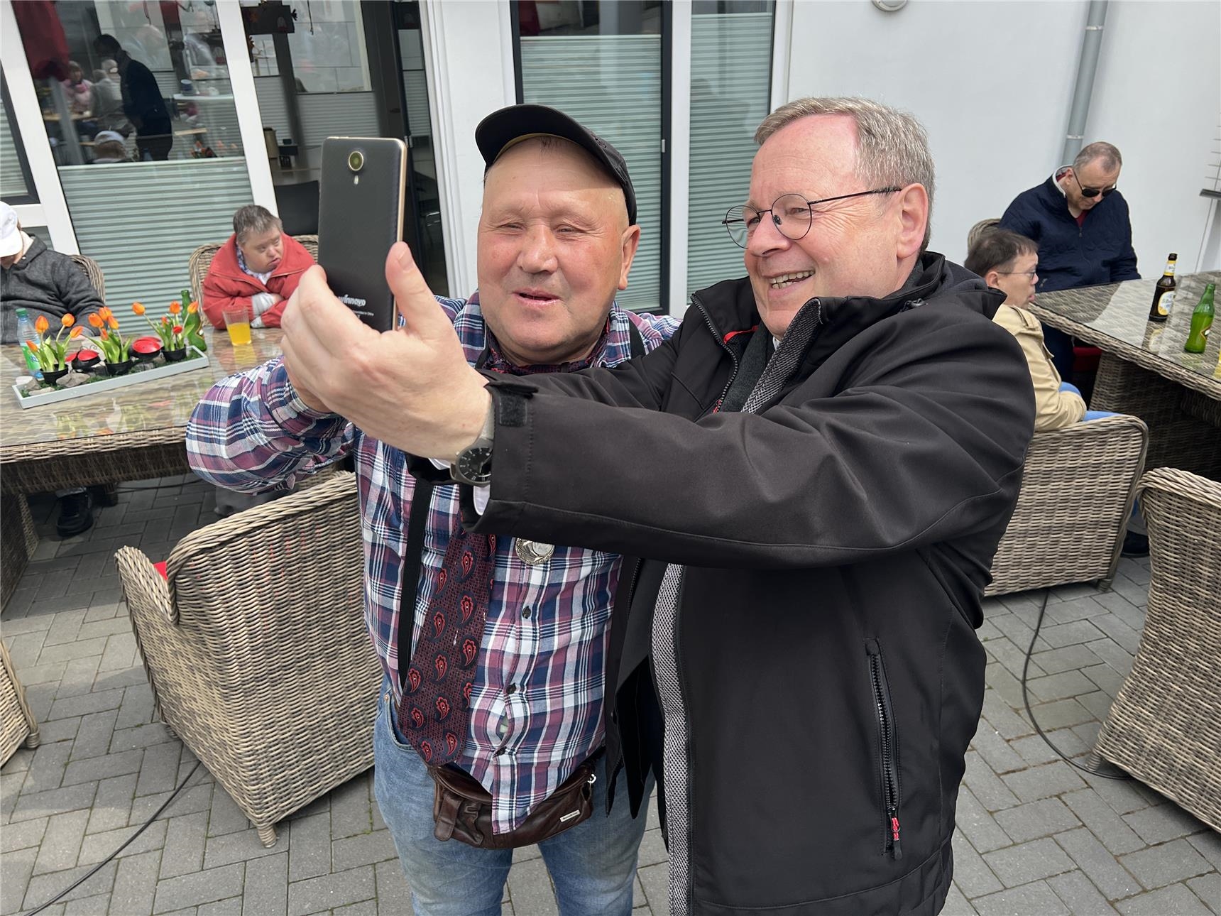 Ein Bewohner macht mit dem Bischof ein Selfi mit seinem Handy. (Caritasverband Westerwald-Rhein-Lahn e.V./Holger Pöritzsch)