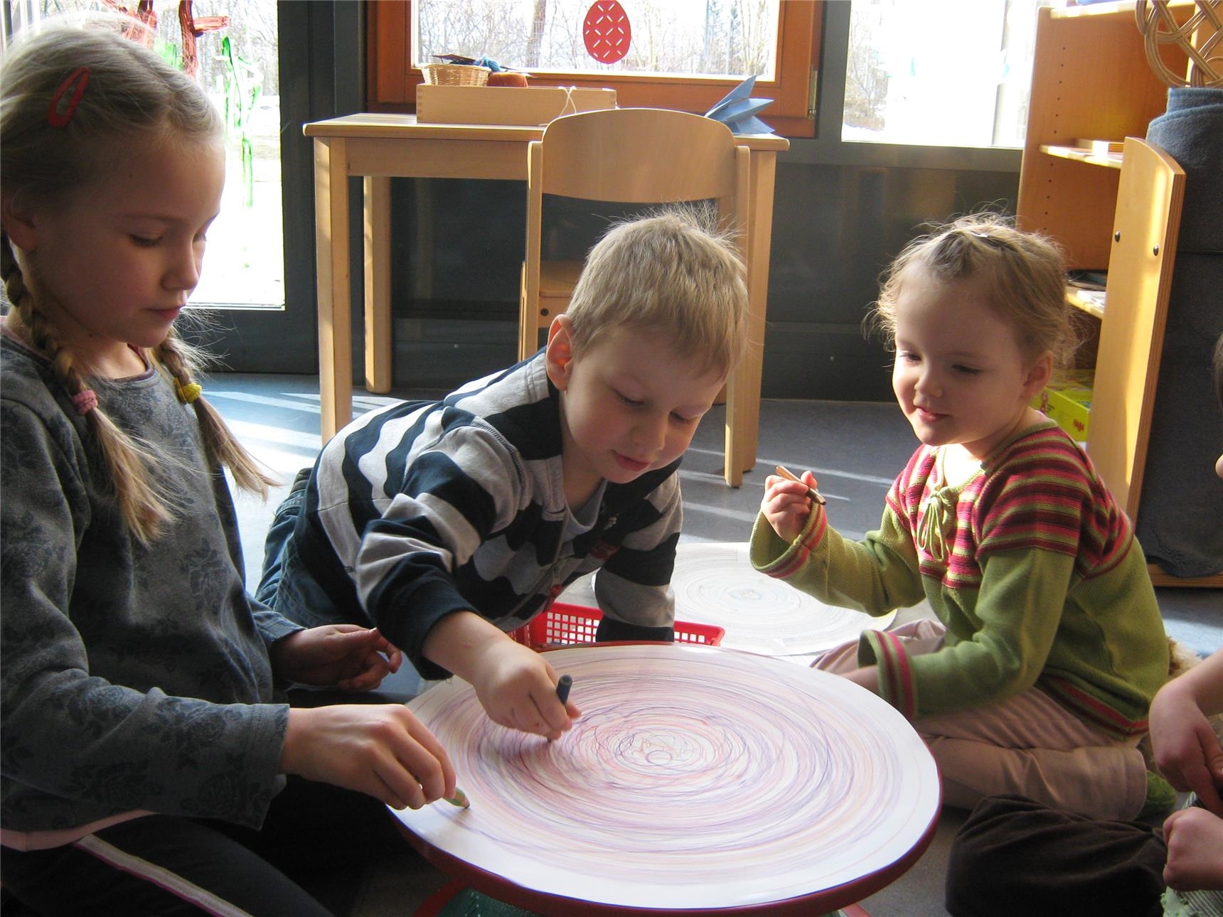 Drei Kinder bemalen ein rundes Stück Papier (Foto: Marco Wagner)