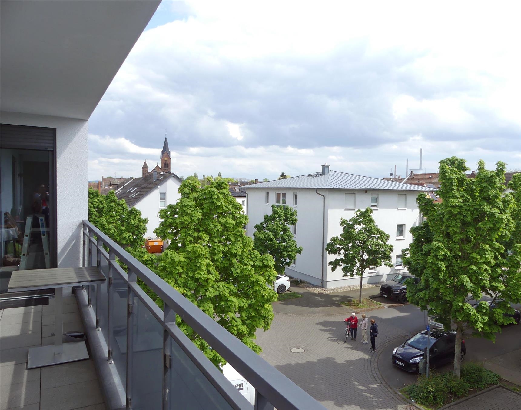 Blick von der Balkontür einer Wohnung des Betreuten Wohnens auf den Balkon, Baumwipfel und umliegende Häuser (Foto: © Caritas Offenbach / Sabine Schilha)