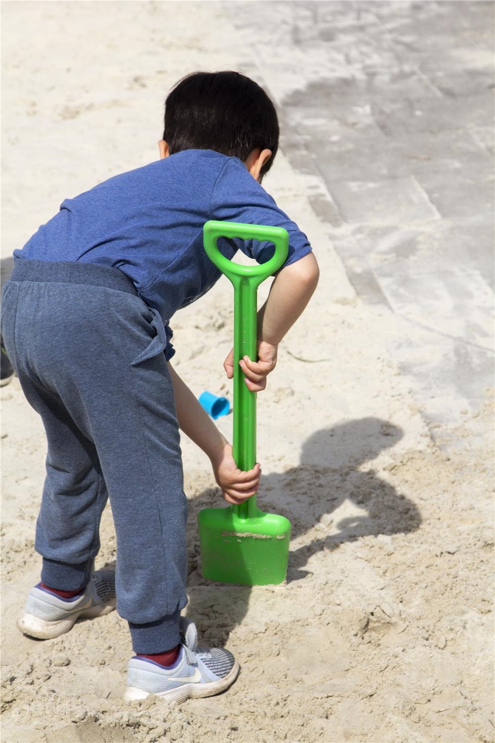 Ein Junge buddelt mit einer Schaufel im Sand. 