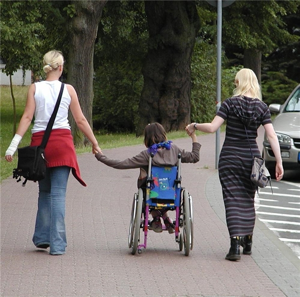 Schulbegleiter mit einem Jugendlichen im Rollstuhl auf dem Weg zur Schule