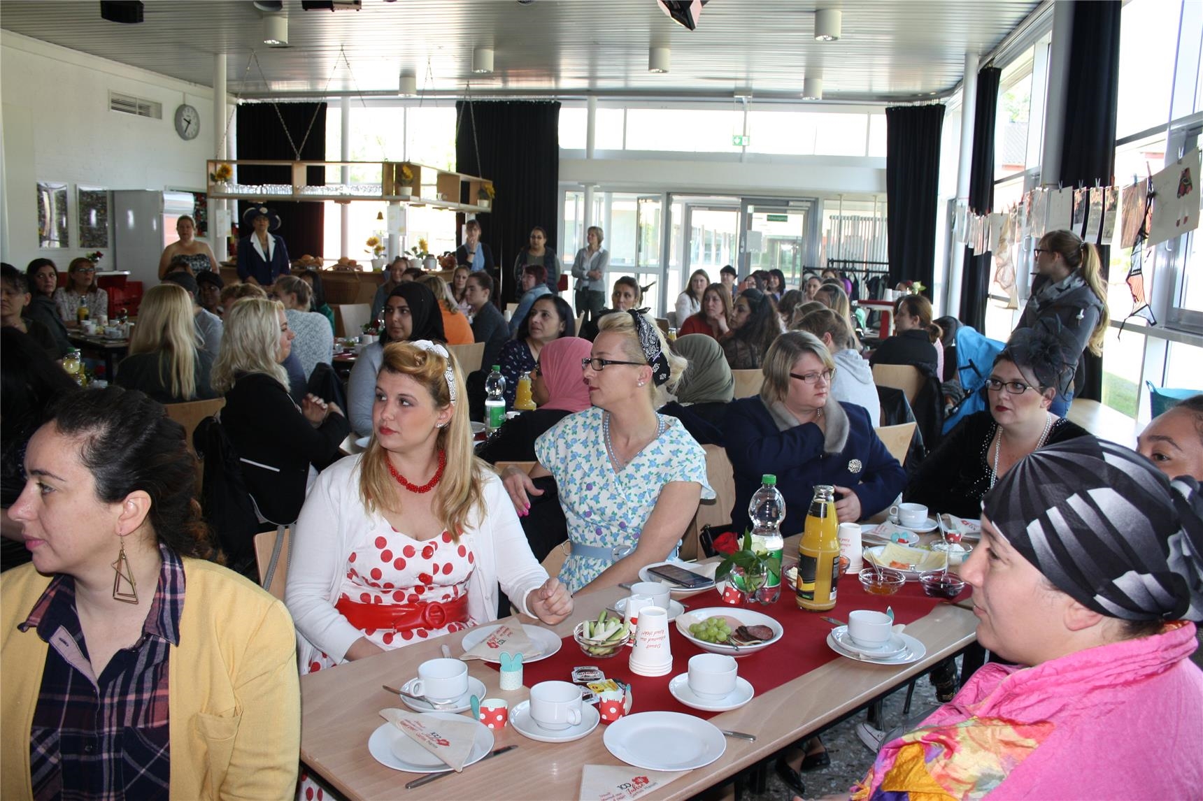 100 Mütter sitzen an gedeckten Frühstückstischen (Caritas Hamm)