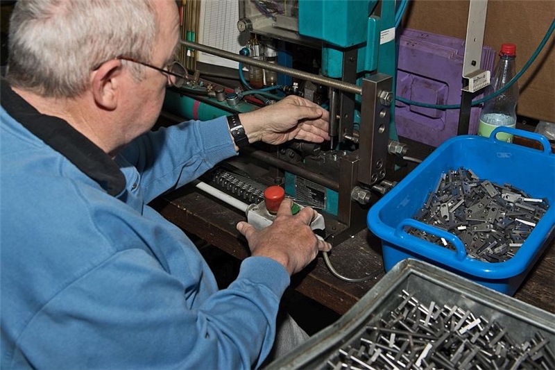 Ein Mitarbeiter fertigt Teile an einer Maschine.