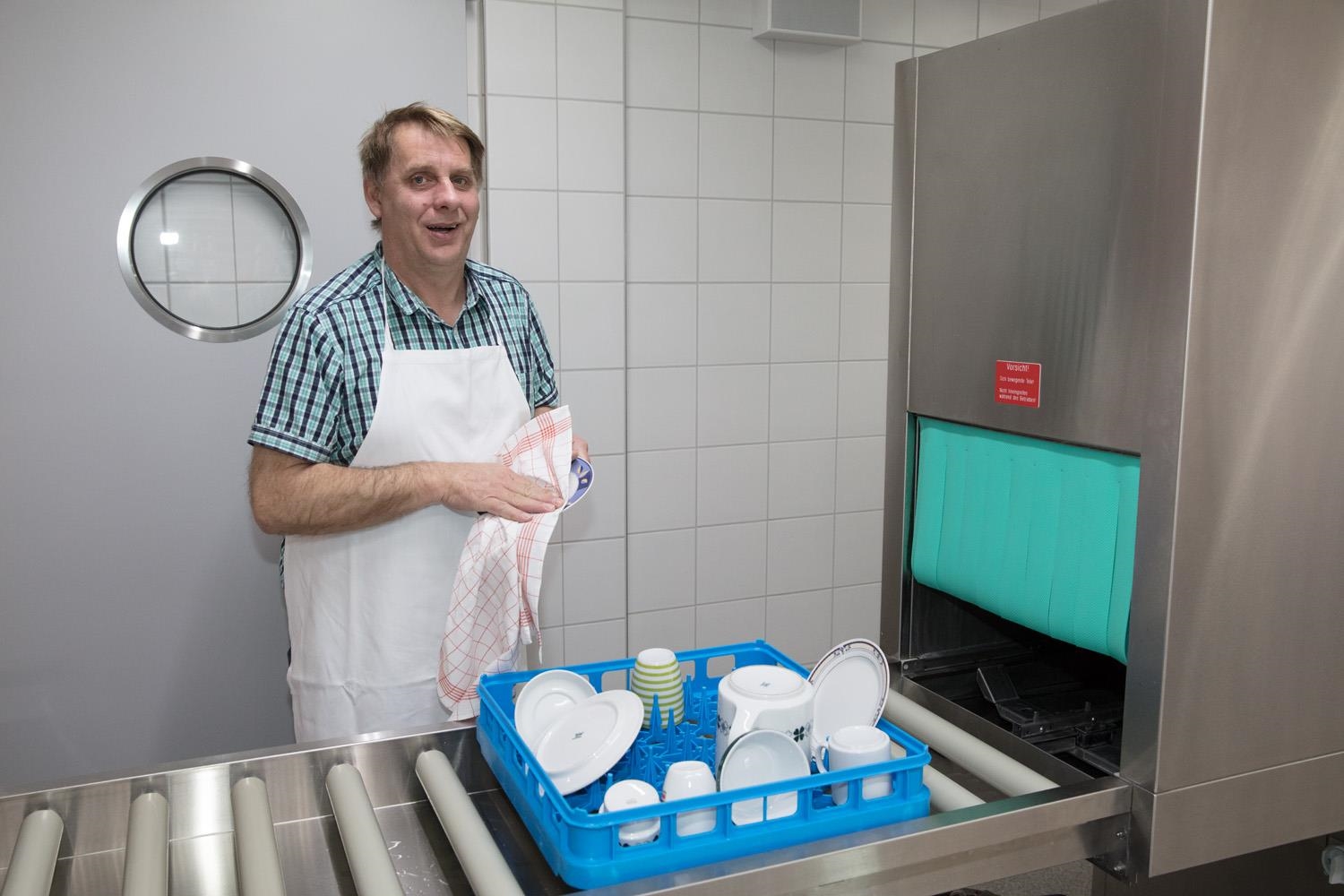 Ein Mitarbeiter beim Abtrocknen von Geschirr.  