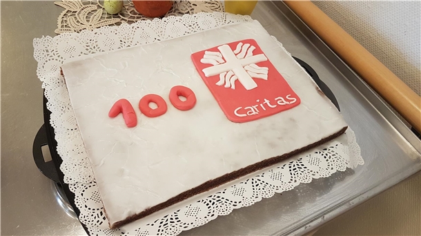 Ein rechteckiger Kuchen mit dem Caritas-Flammenkreuz und dem Schriftzug "100 Jahre"