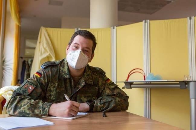 Soldat mit medizinischer Maske füllt Formulare aus