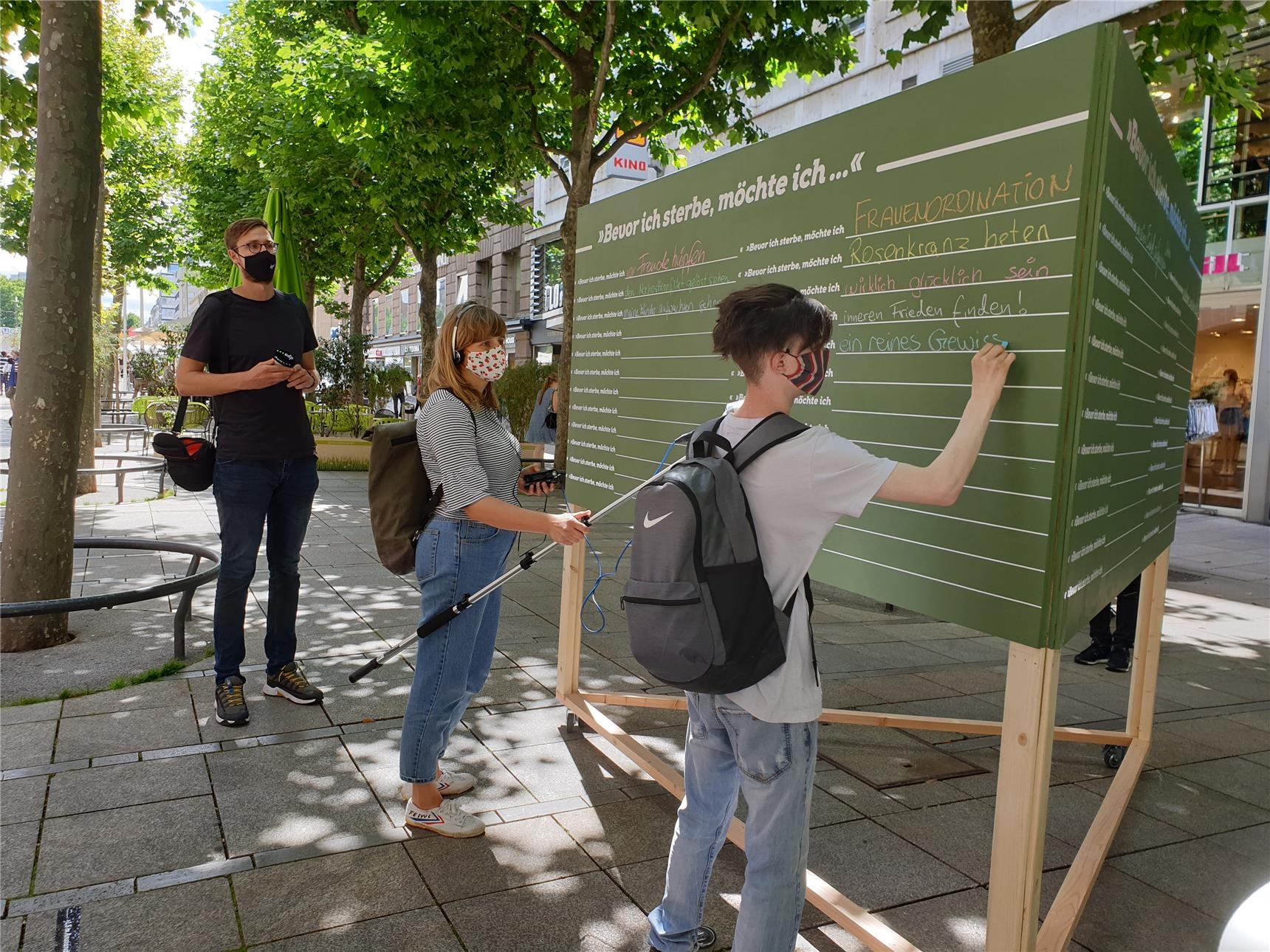 Menschen schreiben an eine Tafel (Caritas Stiftung Stuttgart)