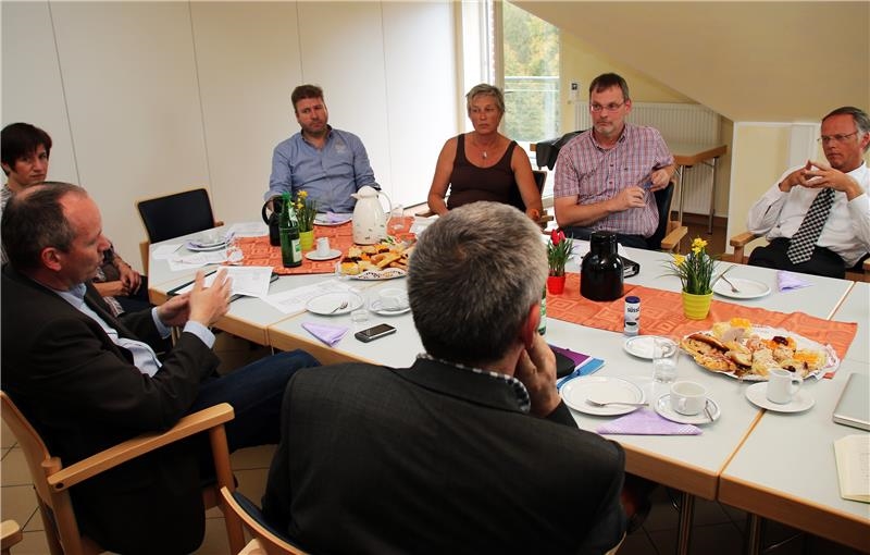 Das Foto zeigt eine Gruppe von Menschen, die an einem großen ovalen Tisch sitzt.