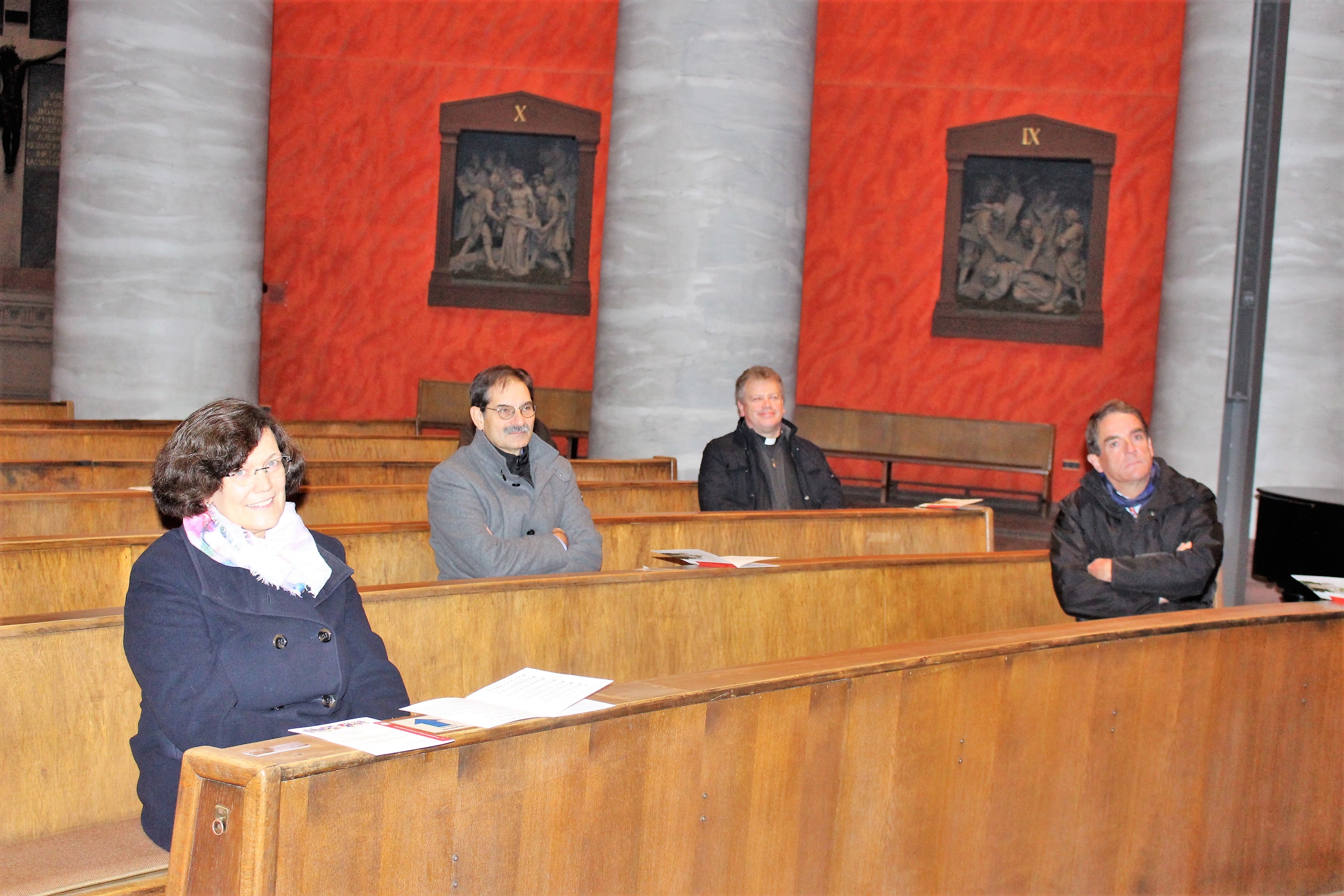 Eine Frau und drei Männer sitzen in Kirchenbänken. (Caritasverband Darmstadt e. V.)