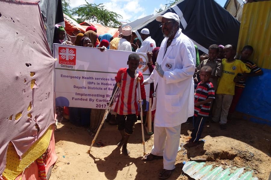 GEsundheitsarbeiter mit einem Jungen mit Gehbehinderung und Krücken (Hussien Abdi Isak / WARDI)