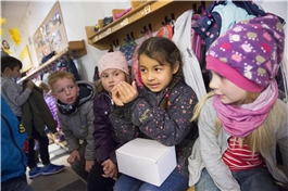 Mehrere Kinder sitzen mit Jacken angezogen im Flur und warten / Dietmar Wäsche