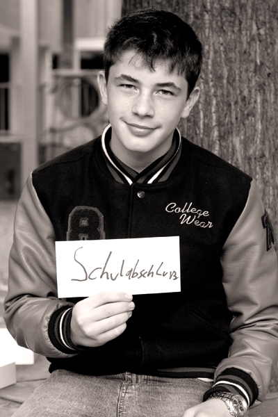 Renè Markus (16) an der Realschule am Rhein in Köln. Er hält ein Schild mit der Aufschrift "Schulabschluss". Die Aufnahme ist in schwarz-weiß. (Tanja Anlauf (Fotoprojekt „Unsere Zukunft“) )
