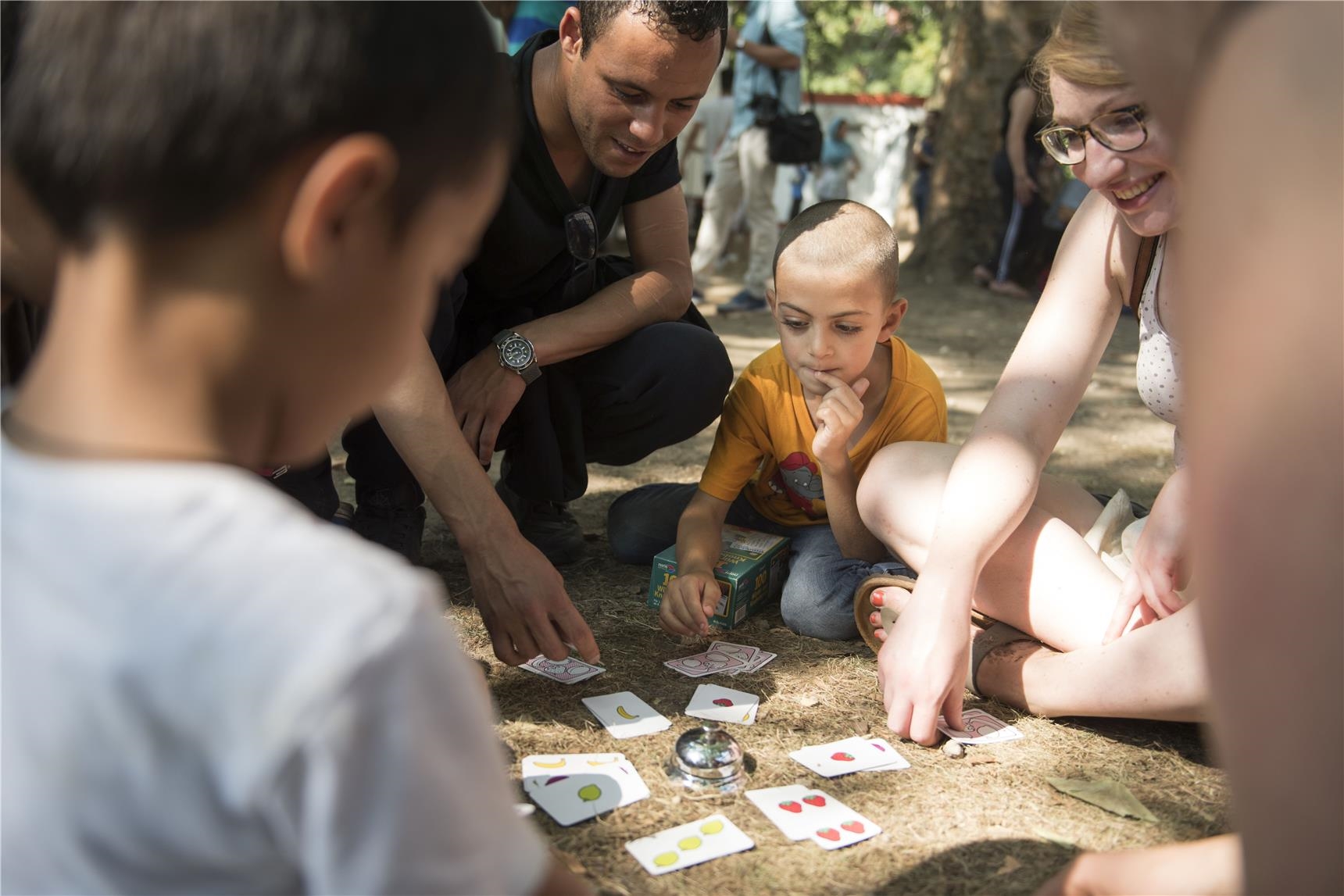 Eine Flüchtlingesfamilie spielt auf dem Boden ein Kartenspiel
