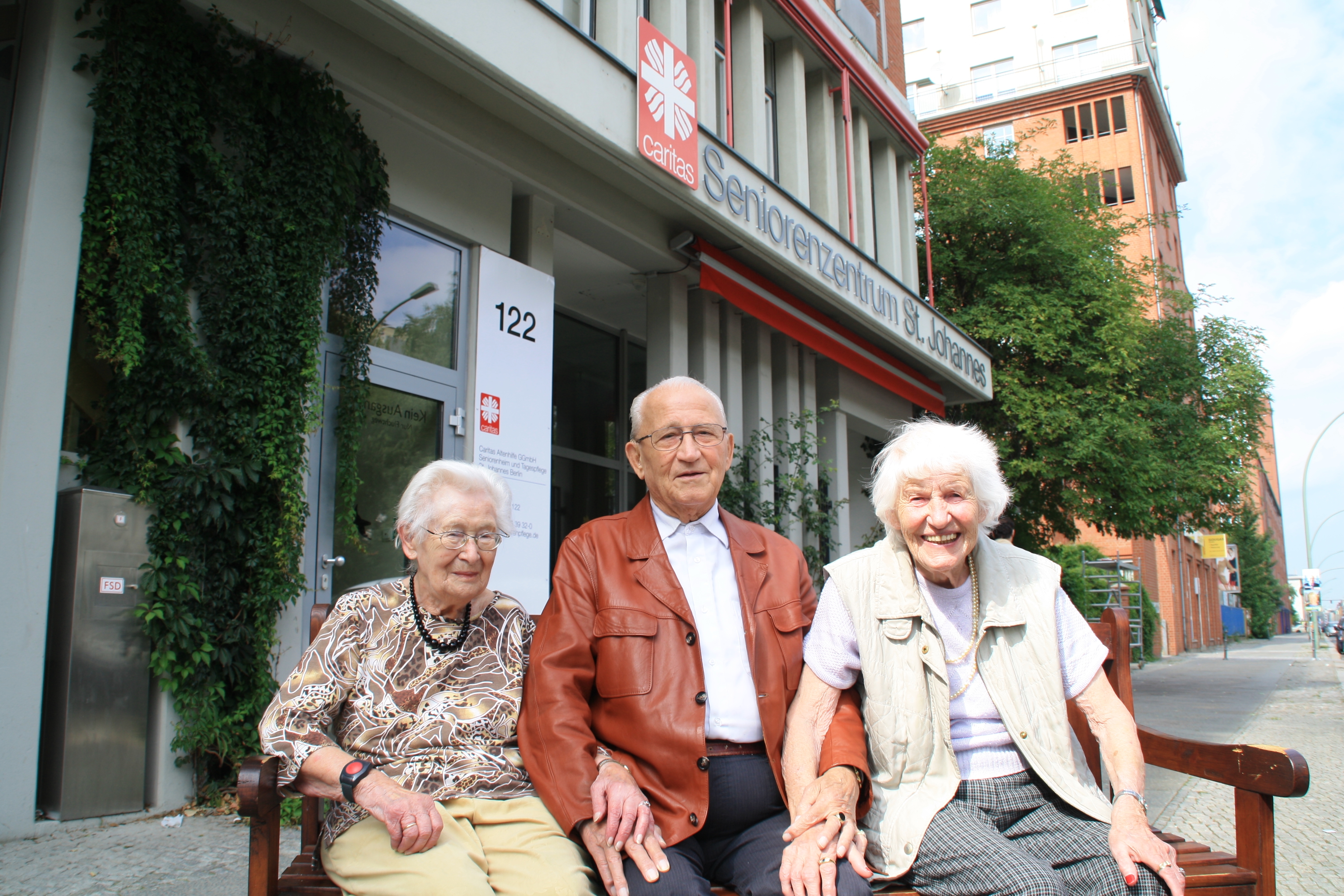 Bewohner sitzen vor dem Eingangsportal des Seniorenheims. 