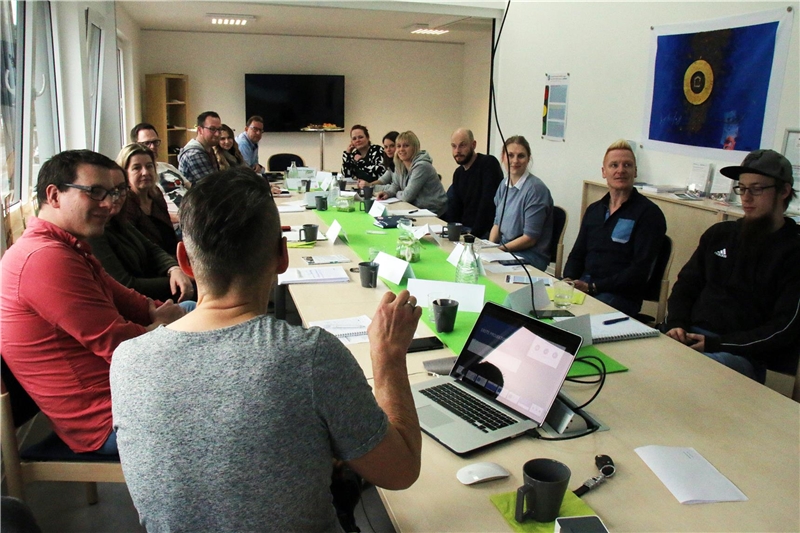 Das Foto zeigt eine Gruppe von Menschen, die an einem langen Tisch sitzt.