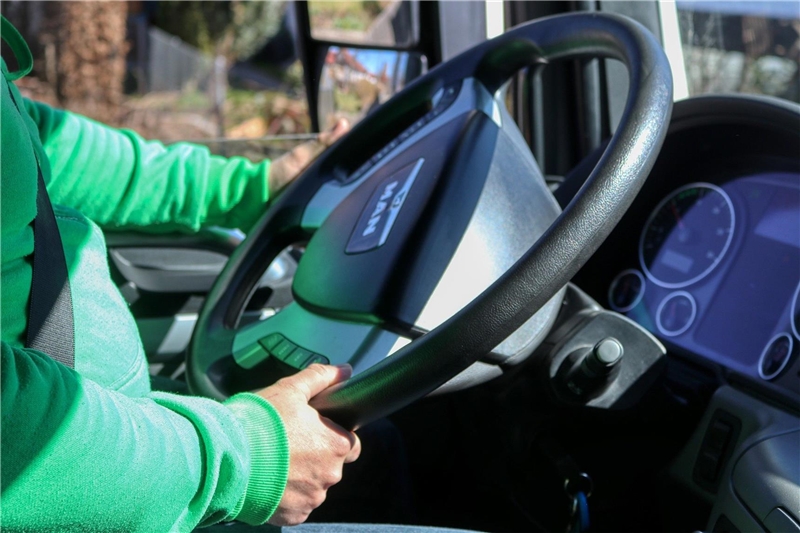 Das Foto zeigt die Hände eines Fahrers am Lenkrad eines Lkw