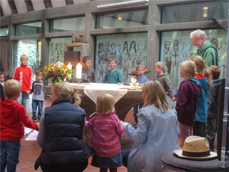 Kinder umstehen mit dem Pastor den Altar von Christus König in Essen. Im Vordergrund ein Hut. (Marie-Helene Gräfin von Merveldt)