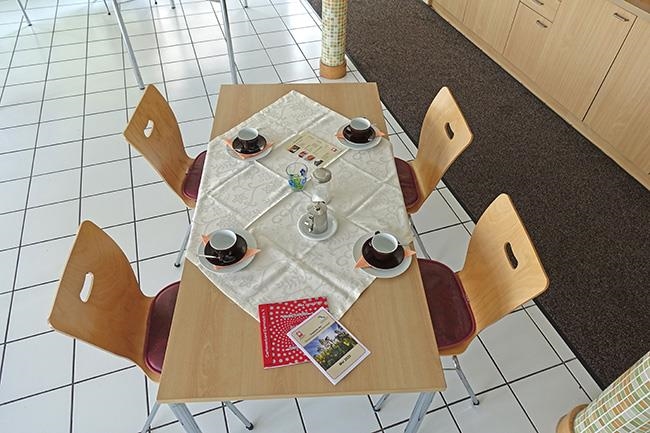 Tisch mit vier Stühlen, darauf Kaffeetassen, eine Menükarte und Flyer mit Angeboten der GPZ (Caritasverband Darmstadt e. V. / Jens Berger)