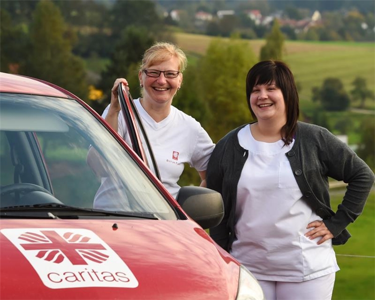 Caritas-Sozialstation - zwei Mitarbeiterinnen vor einem Auto