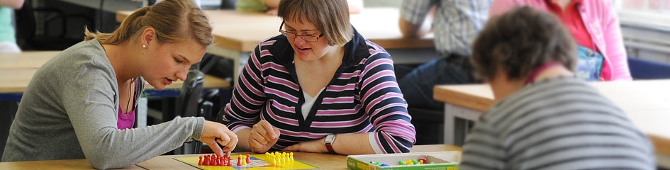 Frau mit Behinderung beim Brettspiel mit Mitarbeiterin (c) KNA/Oppitz