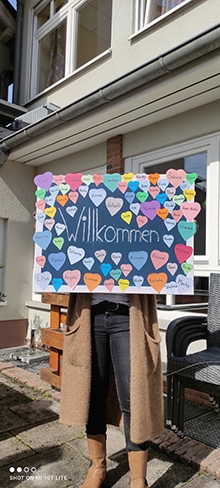 Die Leiterin der Stabstelle Vielfalt Corine Ngahan mit Plakat mit vielen bunten aufgeklebten Herzen mit Namen (Caritasverband Darmstadt e. V.)