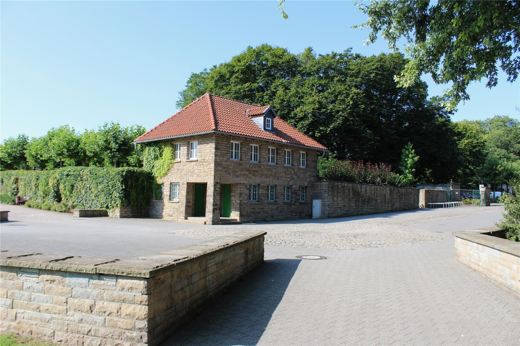 Blick auf eine Weggabelung und ein altes Backsteingebäude im Hoeschpark.W 