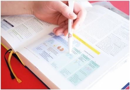 Ein Schüler liest in einem Fachbuch. Mit einem Kuli weist er auf eine Textpassage hin.