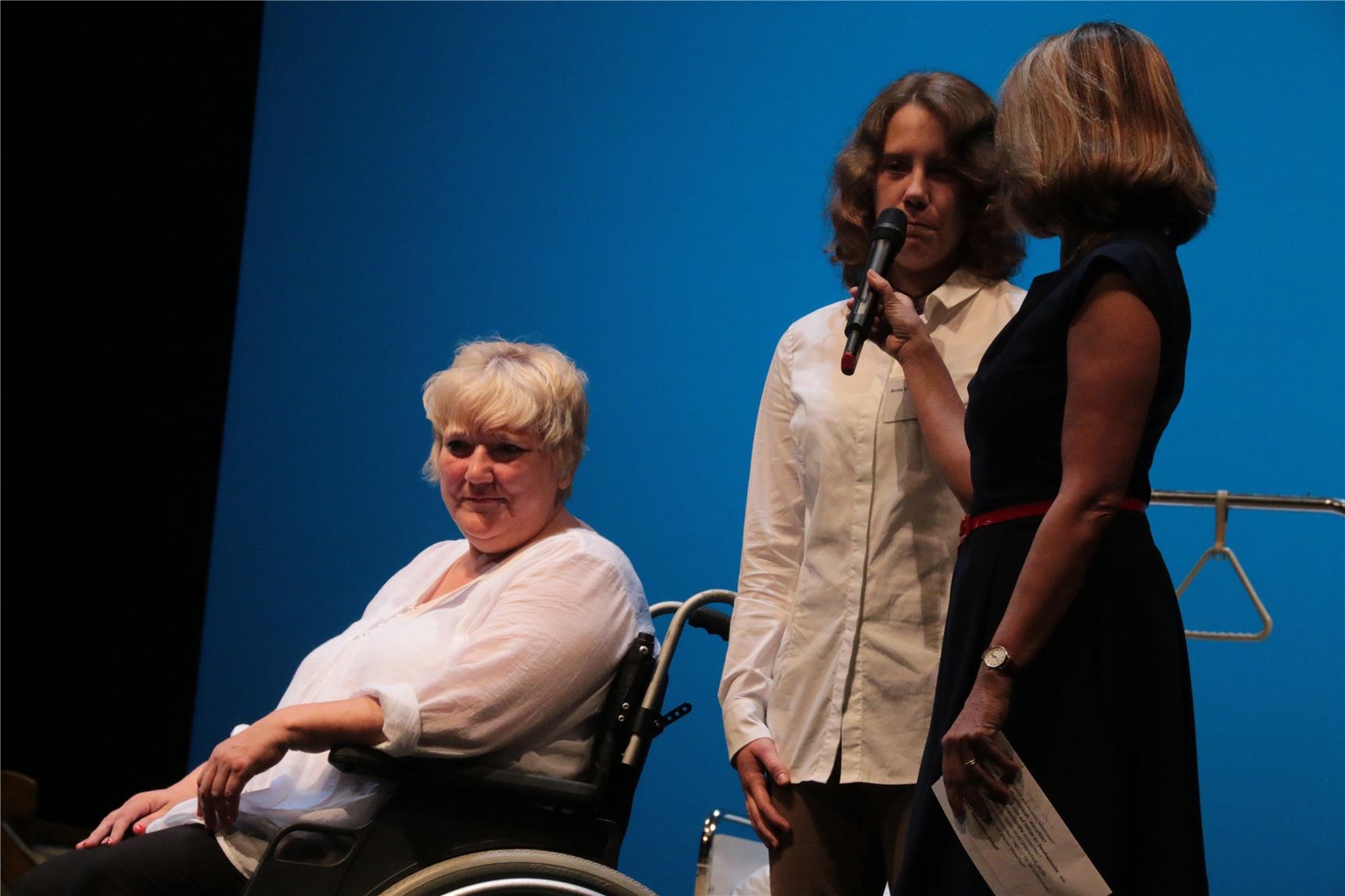 Das Foto zeigt drei Frauen auf einer Bühne, zwei stehend, eine im Rollstuhl (Harald Westbeld)